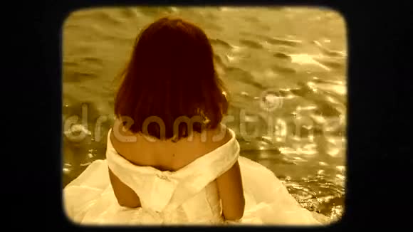 穿着白衣服坐在石头上的年轻漂亮女士视频的预览图