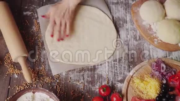 女人在家里厨房里满是面粉的木桌上的砧板上擀面团视频的预览图