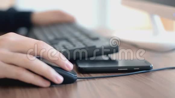 在电脑上工作的人用手点击鼠标和使用智能手机视频的预览图