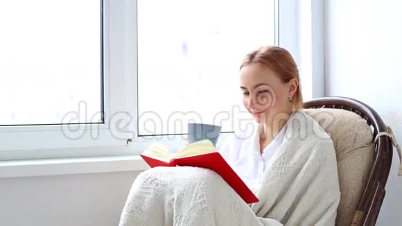 微笑着坐在椅子上拿着书的女学生视频的预览图