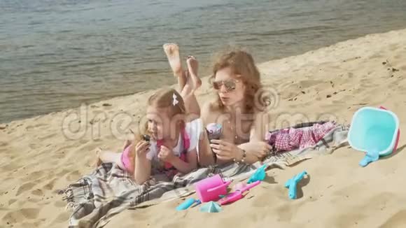 河岸上的妈妈和女儿吃冰淇淋户外娱乐视频的预览图
