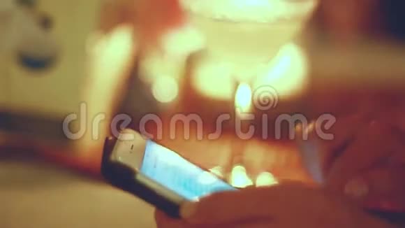 在咖啡馆里用智能手机合上女性的手在美丽的bokeh背景下在夜间酒吧喝鸡尾酒的女人视频的预览图