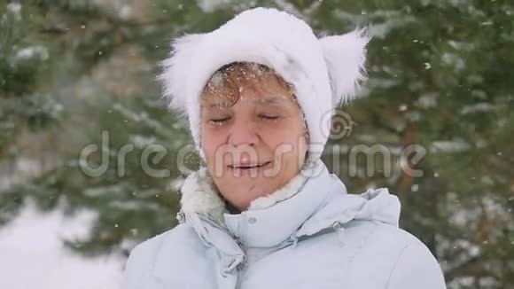 成熟微笑的肖像年老的妇女站在公园里在降雪的缓慢运动1920x1080视频的预览图