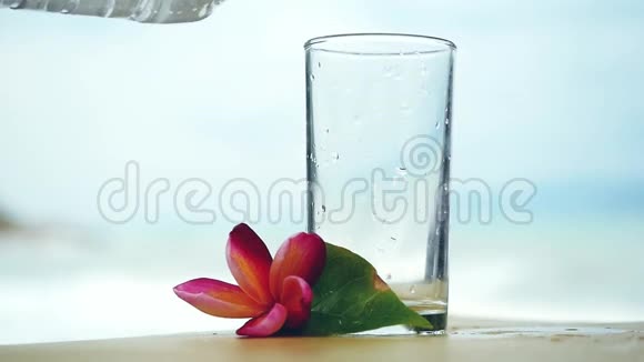 水被缓慢地注入玻璃旁边的弗兰吉帕尼花和禅宗塔模糊的背景视频的预览图