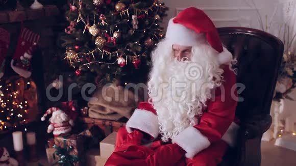 圣诞老人坐在圣诞树旁手里拿着满满一袋礼物视频的预览图