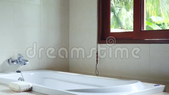 阳光明媚的一天热带岛屿丛林景观的全景窗水疗浴室3840x2160视频的预览图