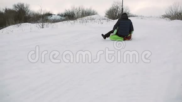 可爱的男人和女孩在冬天滑着雪管上的雪山视频的预览图