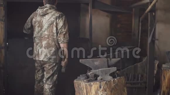 大胡子的青年铁匠在铁匠的铁砧上手工锻造铁水上面放着火花烟花视频的预览图