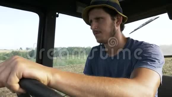 农夫戴着帽子坐在拖拉机舱里用犁骑在田野上视频的预览图
