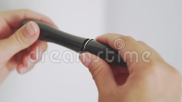 女性手拿着一根带有黑色睫毛膏的管子打开并取出刷子视频的预览图