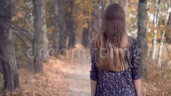 优雅的年轻女性模特戴眼镜和黄瓜连衣裙漫步森林视频的预览图
