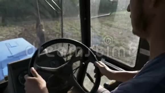 农夫戴着帽子坐在拖拉机舱里用犁骑在田野上视频的预览图