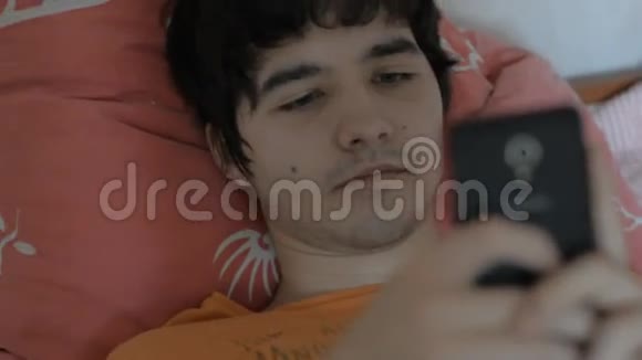 躺在床上有智能手机的年轻男性视频的预览图