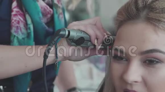 女人和手的化妆设计师针卷发与卷发熨斗视频的预览图