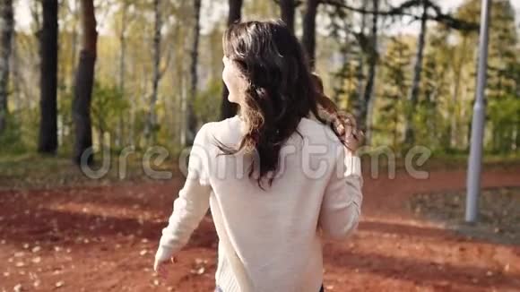一个年轻的女人走在秋天的公园里布鲁内特女人在森林里跳跃和跳舞自由概念视频的预览图