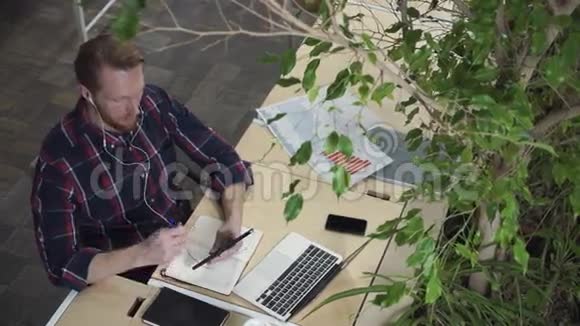 戴着耳机的胡子男人通过平板电脑说话视频的预览图
