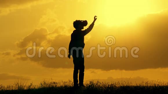日落时在公园里用vr眼镜伸出手臂的男孩的肖像博克赫视频的预览图