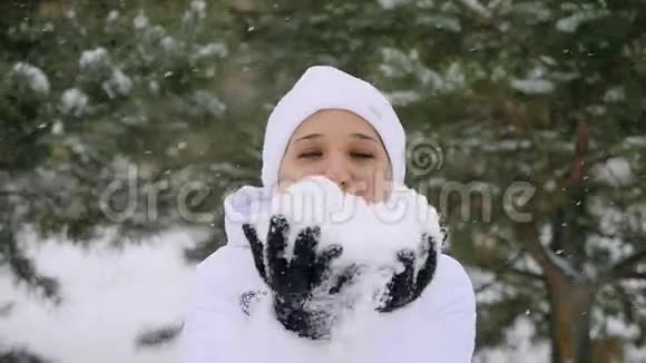 年轻快乐的女人在降雪时吹雪花在缓慢的运动中享受冬天的时光1920x1080视频的预览图