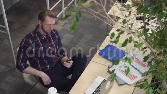 一个长胡子的男人脸上带着傻笑看着智能手机视频的预览图