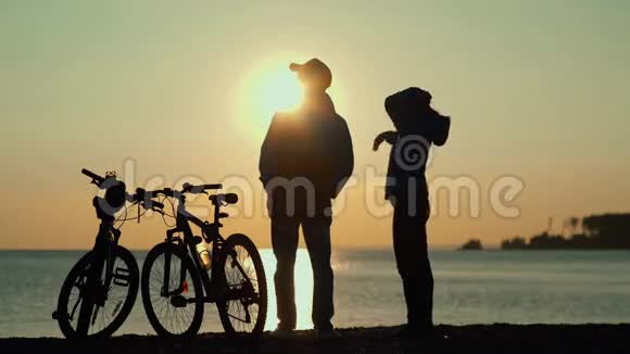海上日落阳光反射在水中有自行车的男人和女人视频的预览图