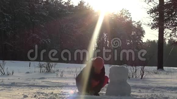 这个女孩冬天在树林里堆雪人太阳很亮视频的预览图