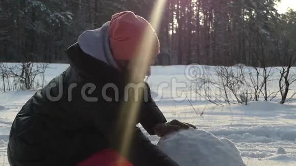 这个女孩冬天在树林里堆雪人太阳很亮视频的预览图