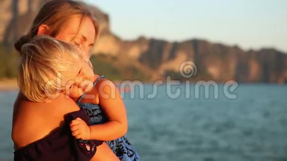 金发女人带着小孩欣赏悬崖上的日落视频的预览图