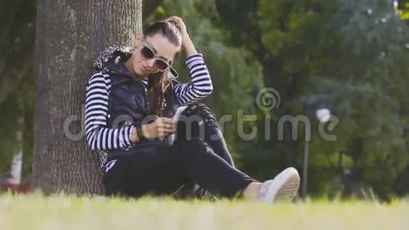 迷人的年轻女子在美丽的秋天公园里用手机聊天视频的预览图