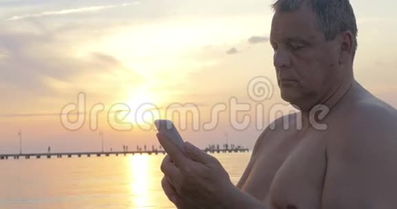 日落时海边有智能手机的人视频的预览图