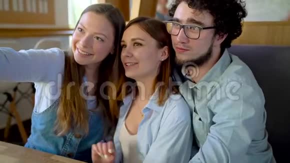 三个朋友坐在咖啡馆里玩得开心交流自拍视频的预览图