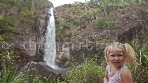 特写小女孩在石头上与瀑布级联视频的预览图