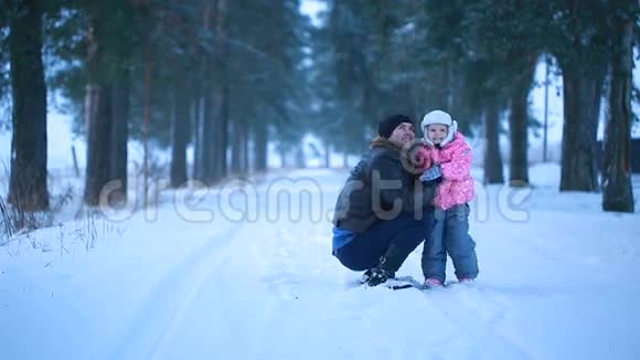 爸爸和女儿快乐地拥抱在冬天的公园里视频的预览图