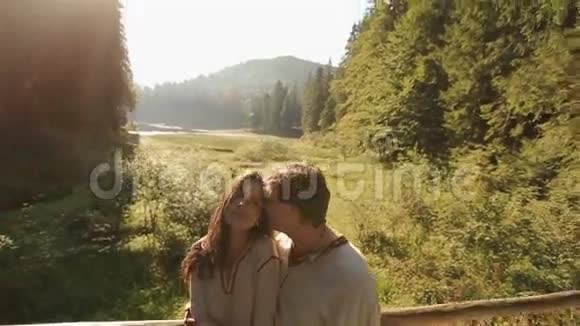 美丽的年轻夫妇穿着传统的乌克兰服装轻轻地拥抱在山上的木桥上雄伟壮观视频的预览图