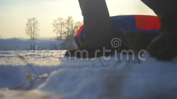 女孩在冬季公园里滑雪年轻的女人在山上背着雪橇在阳光下缓慢地运动视频的预览图