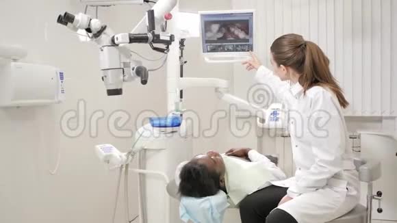 迷人的漂亮女孩医生牙医年轻的非裔美国男性病人在牙科诊所的椅子上医学卫生视频的预览图