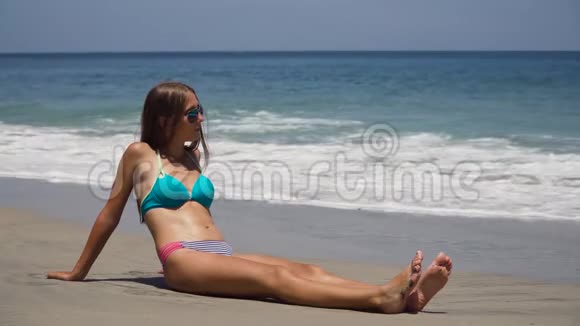戴着太阳镜的女孩坐在海滩上视频的预览图