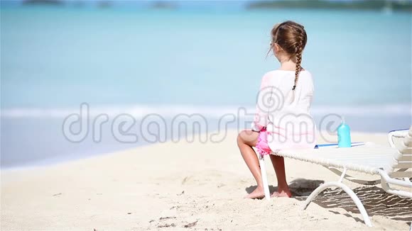 在白色沙滩上晒太阳的小女孩视频的预览图