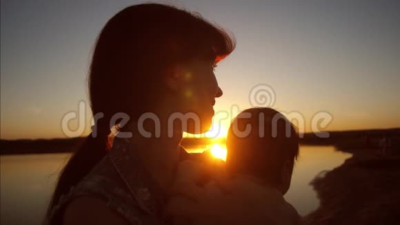 妈妈在日落时抱着孩子在阳光下慢动作视频的预览图