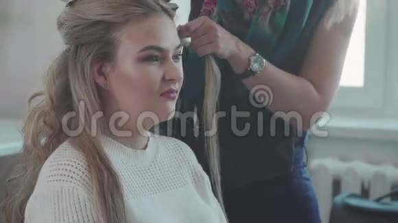 女理发师用卷发熨斗做卷发健康的头发视频的预览图