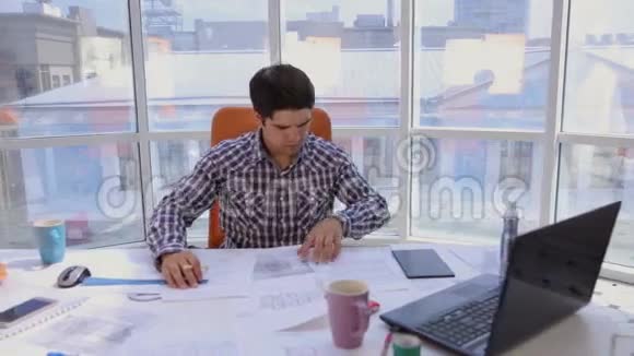 一个自信而有魅力的商人在一个轻盈现代化的办公室里用图纸蓝图工作商业概念视频的预览图