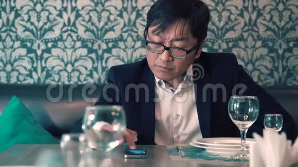 穿西装的亚洲男人在咖啡馆里等着他们的食物长时间等待点餐紧张视频的预览图
