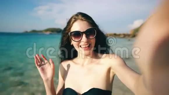 年轻快乐的女人在海边用智能手机上网和朋友聊天视频的预览图