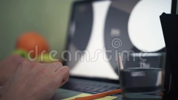 年轻人的手放在笔记本电脑的键盘上桌子上有一杯水和铅笔视频的预览图