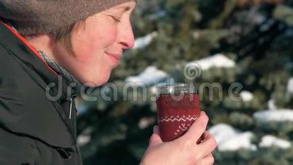 女人在森林里喝着热茶美丽的冬天风景和雪杉树视频的预览图