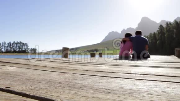 年轻浪漫的情侣坐在湖边的木船尽头视频的预览图