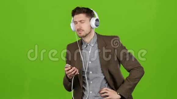 男人通过耳机听音乐跳舞和唱歌绿色屏幕视频的预览图