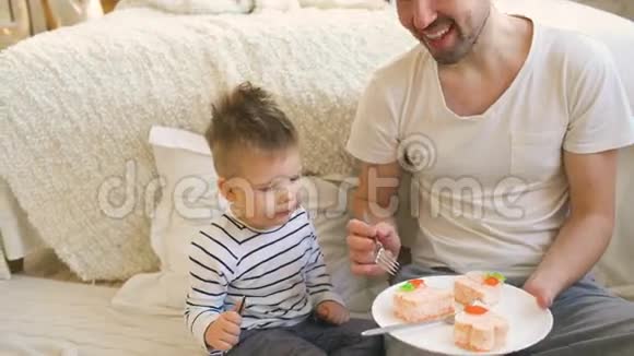 小可爱的男孩和小爸爸在卧室里吃蛋糕庆祝生日视频的预览图