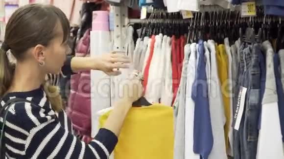 年轻的母亲在一家零售服装店买童装查看项目视频的预览图