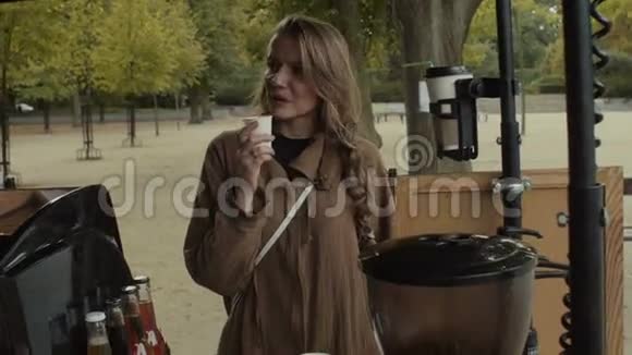 在阳光明媚的秋日户外带着一杯热饮料的年轻漂亮女人视频的预览图