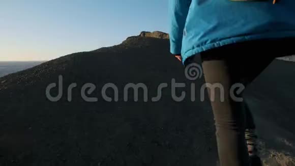 年轻迷人的女孩徒步旅行者沿着沙质悬崖或海边悬崖举起双手看着金色视频的预览图